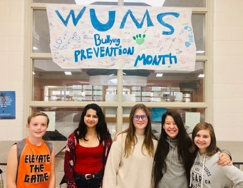students standing with anti bullying poster
