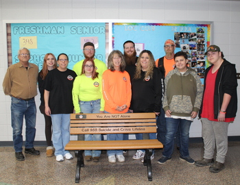 Representatives from the donations standing in behind one of the donated benches