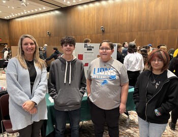 Jennifer Howard, Maz Berens, Logan Bush, and Eva Perez standing in front of poster