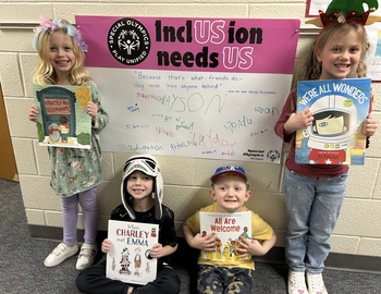 Four students in Mrs. Neely's classroom holding up books read during the week.