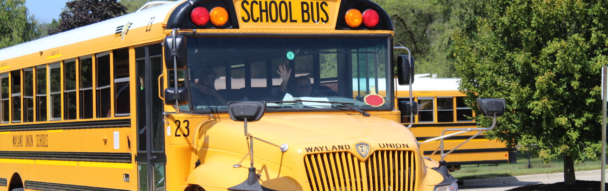 Bus driver waving as they pass by