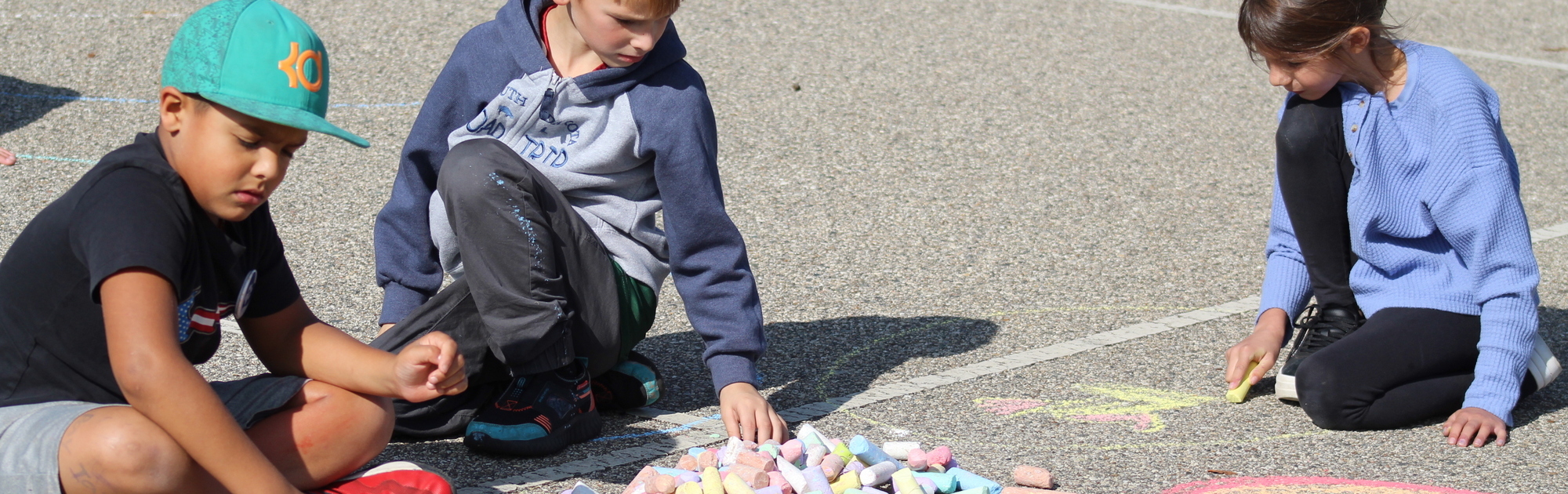 3 elementary students utilizing chalk