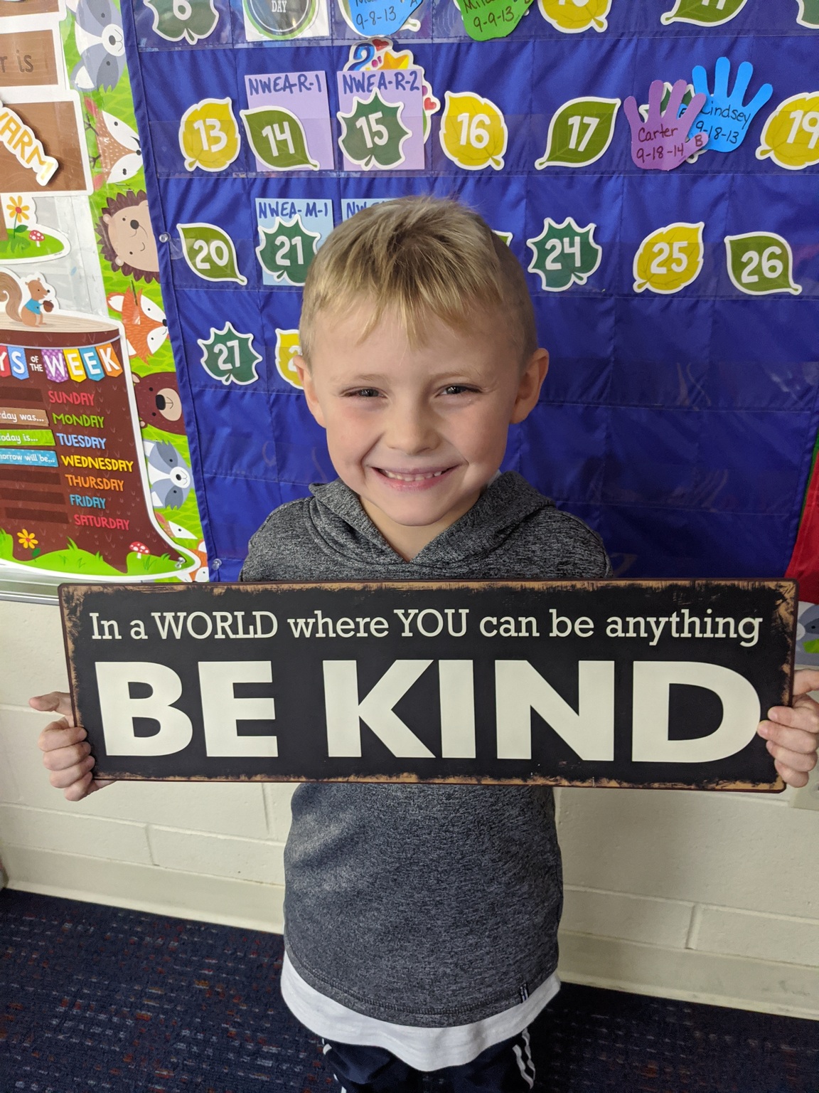 student holding a sign that says Be Kind