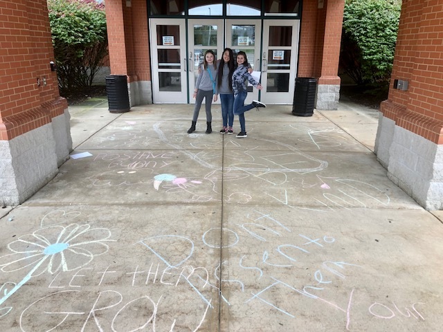 students standing with sidewalk chalk positive messages